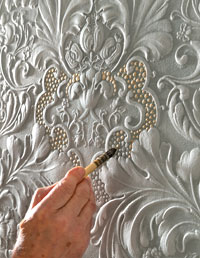 Lincrusta Decorator Detail - Der Raumausstatter oder Maler tupft auf die weiße Farbe gelb goldene Highligts mit einem kleinen Pinsel